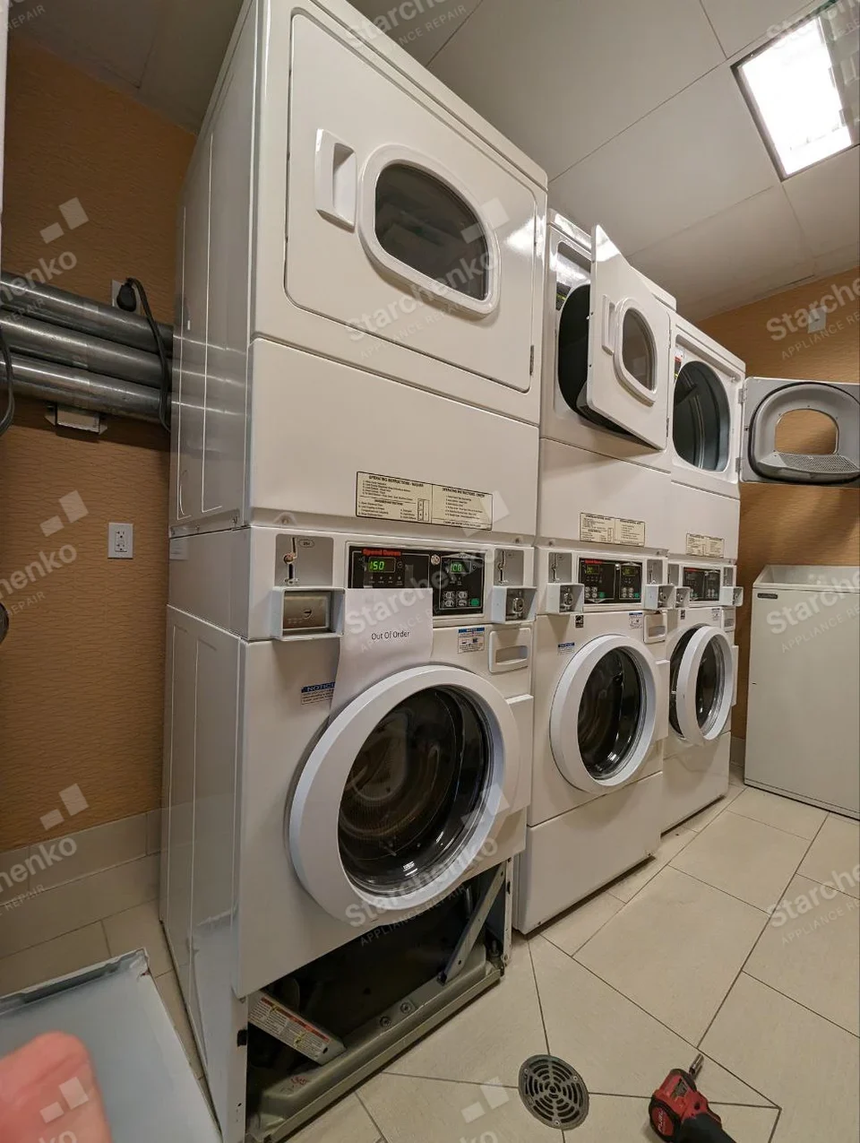 Speed Queen lettering on control of lower front-load washer, coin mechanism and lower access panel removed, dryer stacked above.
