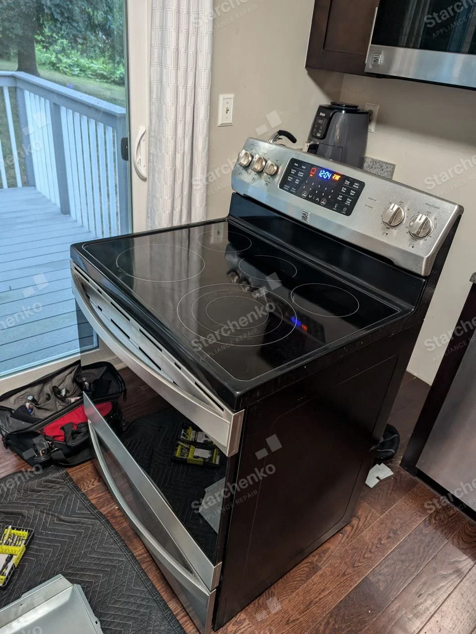 LG repair: Electric smooth-top range with oven door open, rear digital control illuminated, maker badge too small to read.