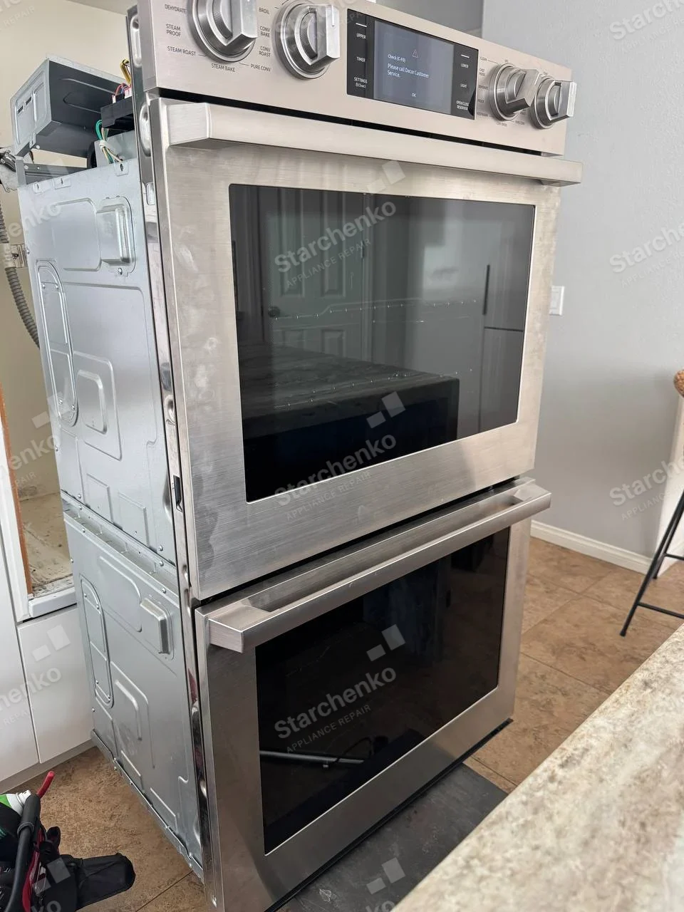 Samsung repair: Built-in double oven pulled from wall cabinet, upper side electronics exposed.