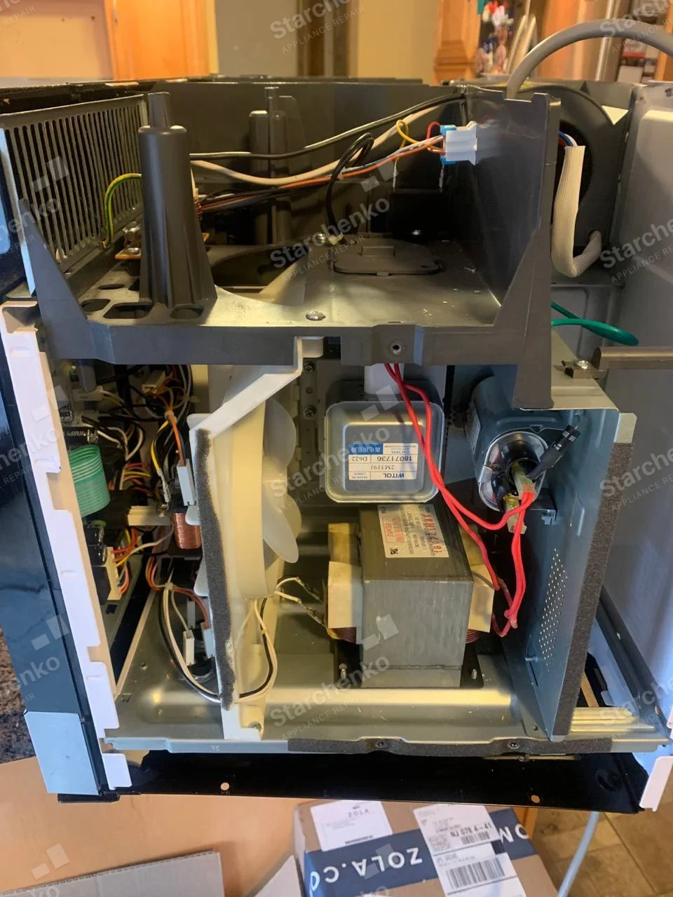 Samsung repair: Open microwave chassis with magnetron, large transformer, cooling fan and wiring, no clear external form factor.