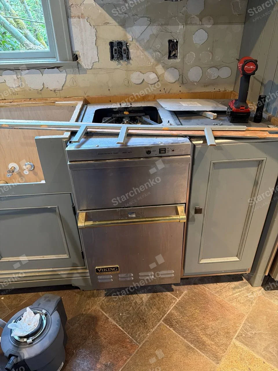 VIKING badge on front lower panel of built-in dishwasher with countertop removed, upper fascia has Heavy Duty cycle lettering.