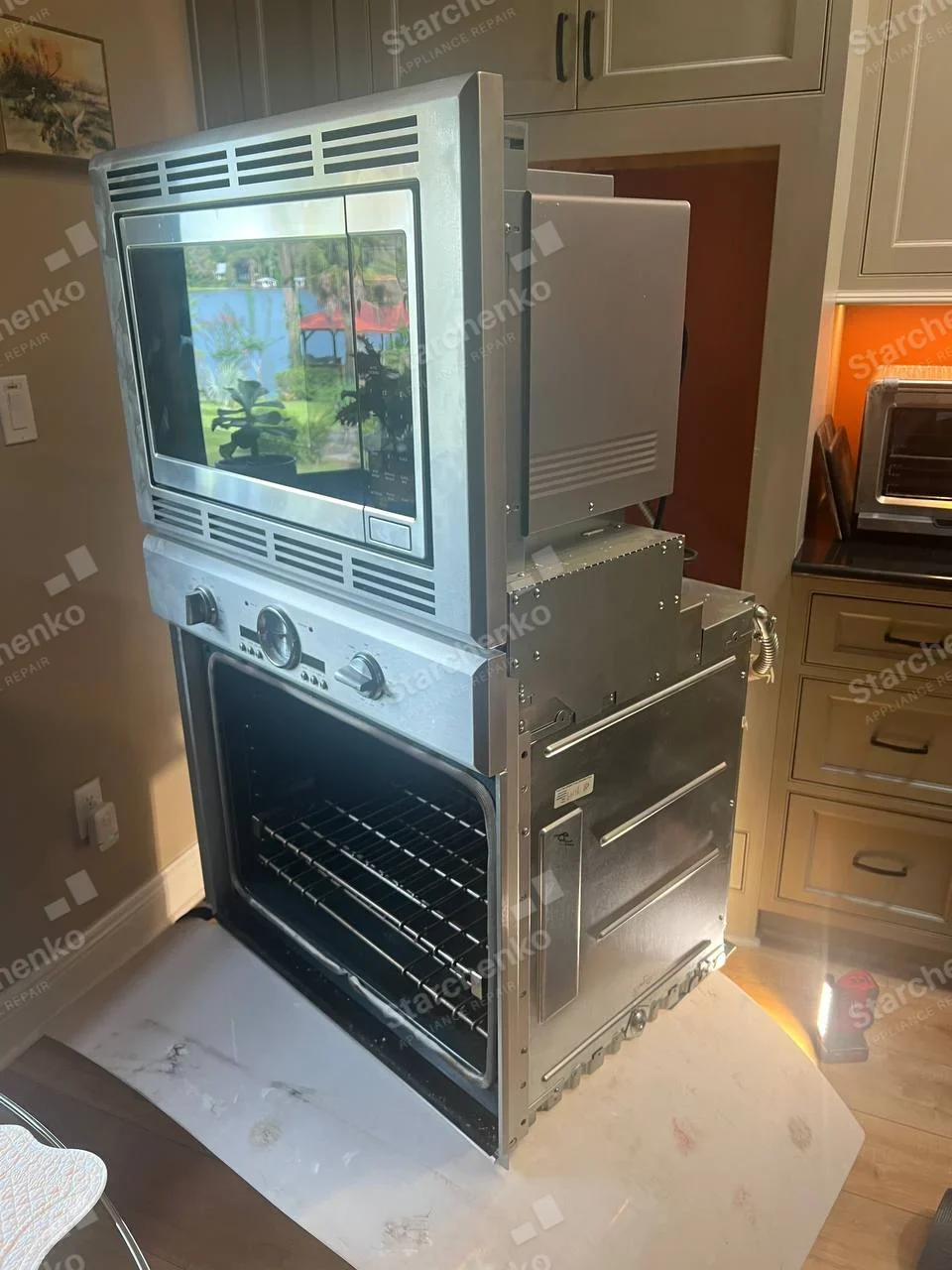 Samsung repair: Built-in microwave mounted above oven in combined wall assembly removed from cabinetry, lower oven open.