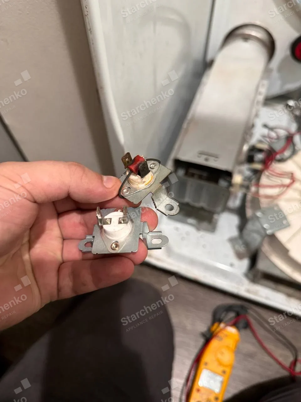 Kenmore dryer repair: Close-up two thermal cutoffs held before an open dryer heating duct and exposed wiring.