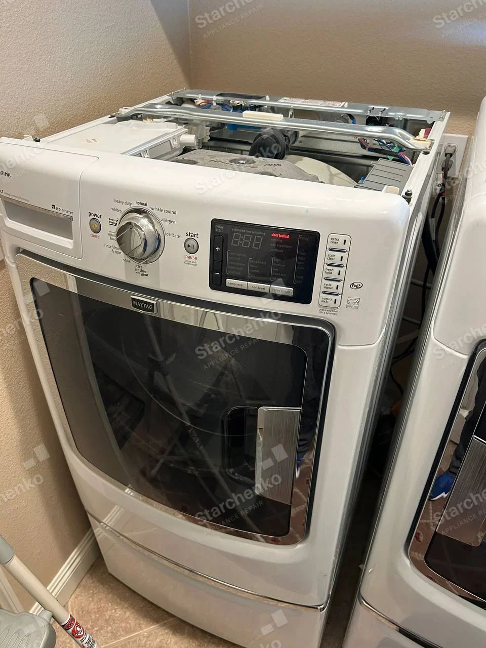 Maytag front-load washer with top cover removed, showing dispenser and upper tub area.