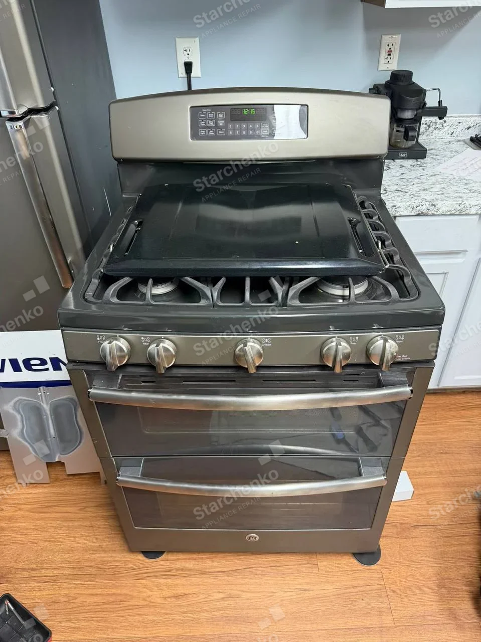GE medallion on lower oven door of ordinary freestanding gas range with two oven cavities, a removed glass panel rests over burners, not a verified griddle.