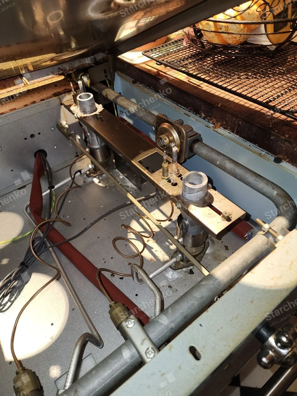 Kenmore repair: Open gas burner manifold of cooking range under lifted top.