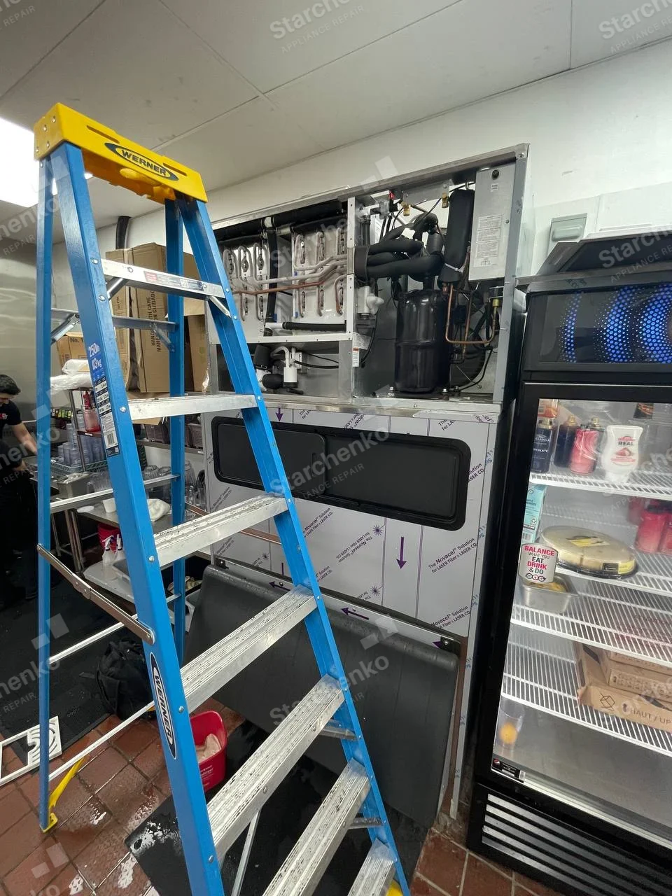 Kold-Draft repair: Large commercial modular ice-making head with exposed vertical evaporator plates and water circuit above a wide ice-storage bin with dark access doors.