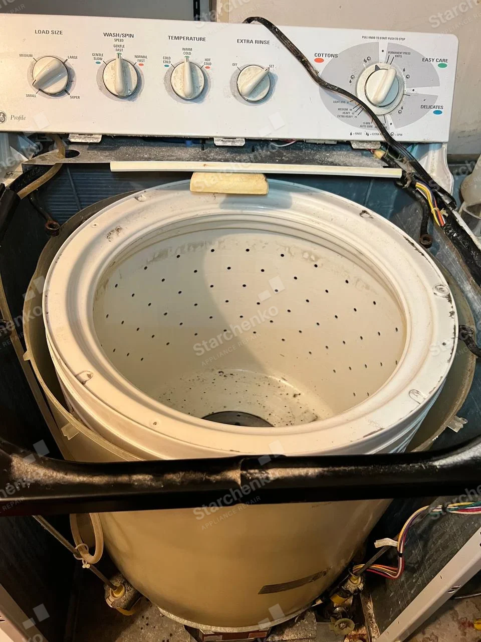 GE Profile top-load washer opened from above with wash basket and tub exposed.