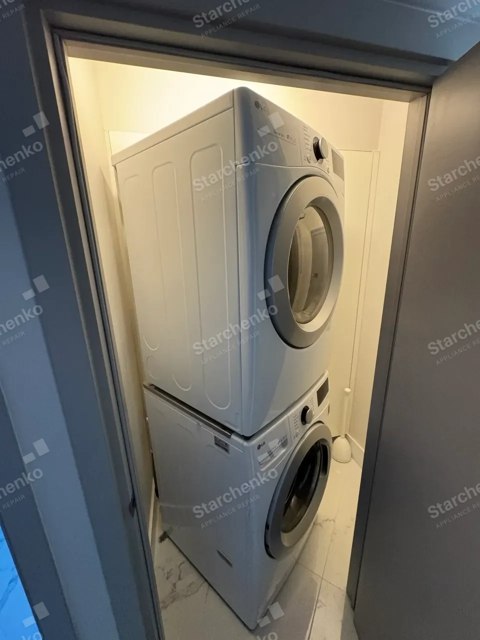 White LG dryer stacked above a washer in a narrow laundry closet