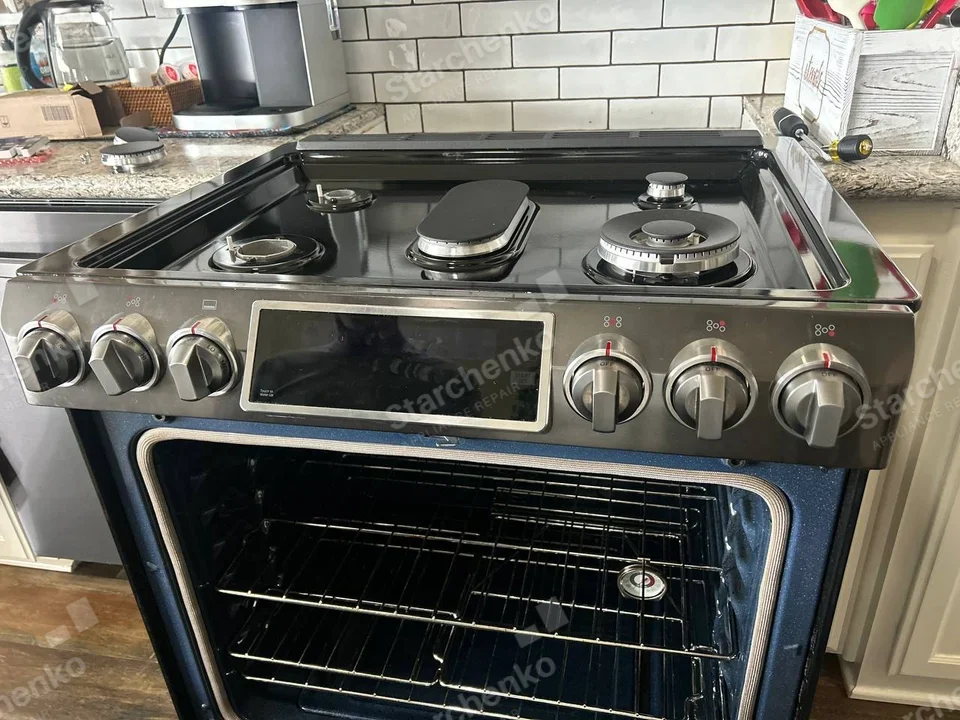 Kenmore repair: Gas burner heads on cooktop with several caps removed, oven door removed, cavity open with thermometer inside.