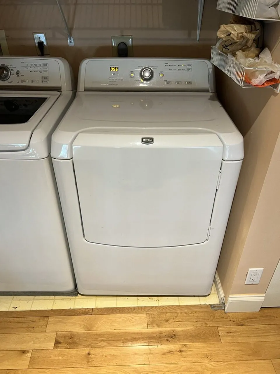 White Maytag dryer next to a top-load washer in a laundry closet