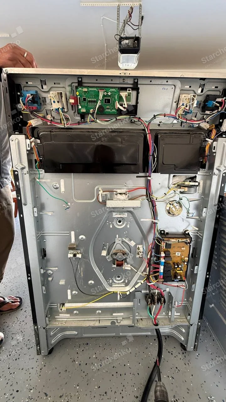 Kenmore repair: Rear of freestanding electric range opened, showing cooktop wiring, control boards and convection fan mount, no main-appliance badge.