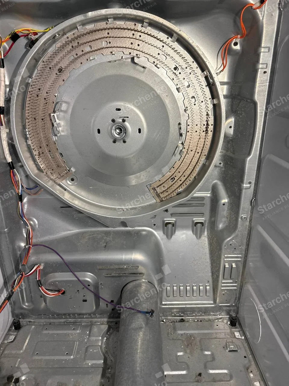 Kenmore dryer repair: Heater ring and exhaust tube visible behind dryer drum, with panel removed, no appliance wordmark.