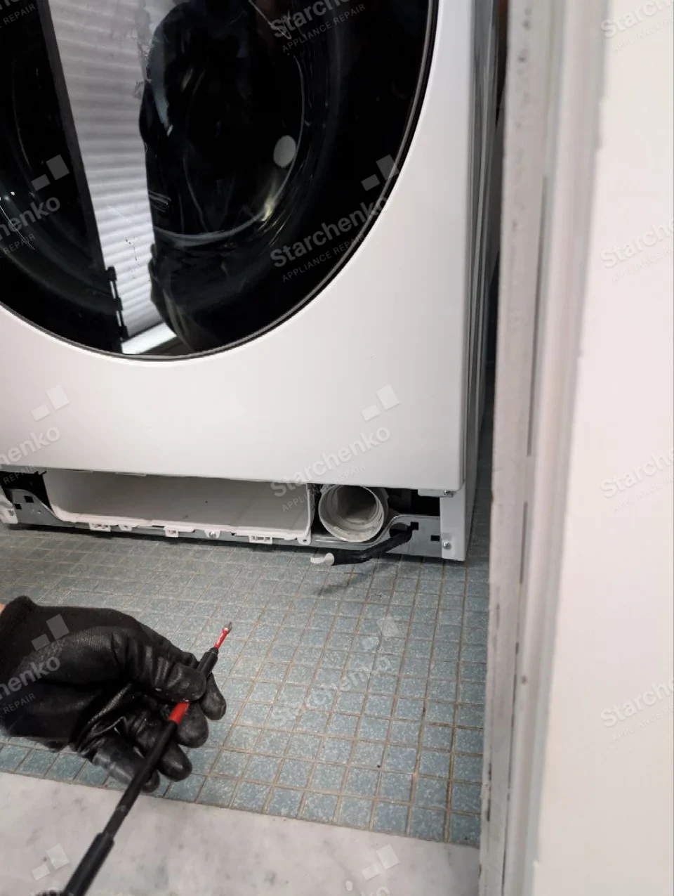 Electrolux repair: Lower front of front-load washer with service toe panel removed and pump filter opening visible, no maker mark.
