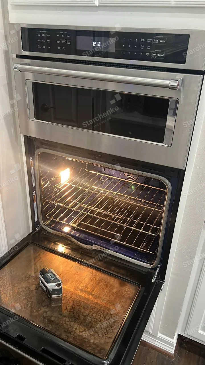 Frigidaire repair: Lower built-in oven open with inspection instrument on door, microwave mounted above.