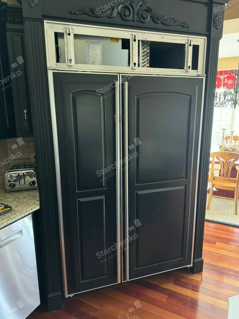 Viking repair: Two full-height paneled side-by-side refrigerator doors, service trim above doors is removed, showing upper compressor compartment.