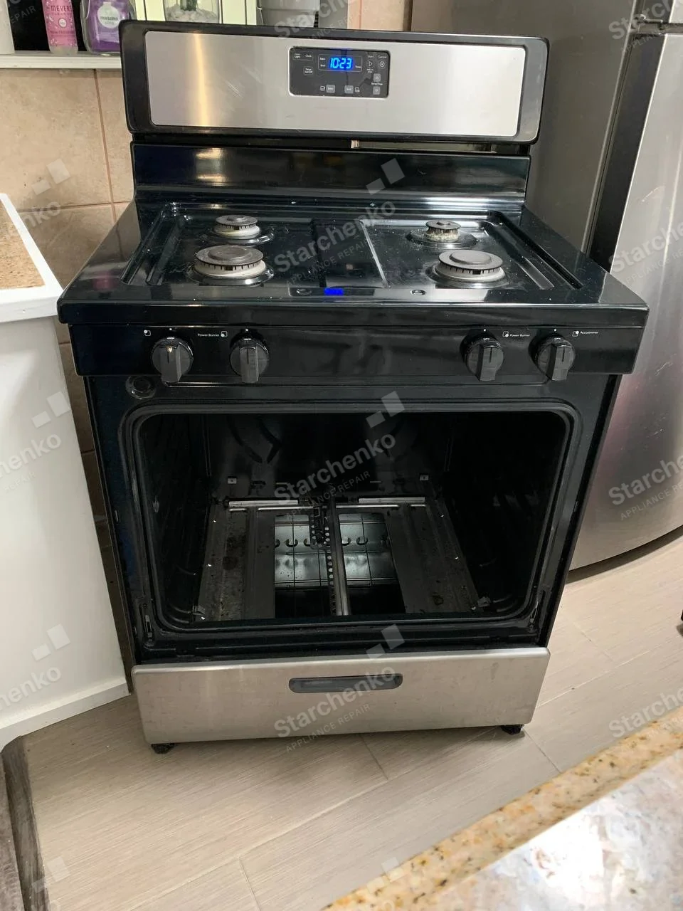 Frigidaire repair: Four-burner gas range with oven open and lower cavity components exposed.