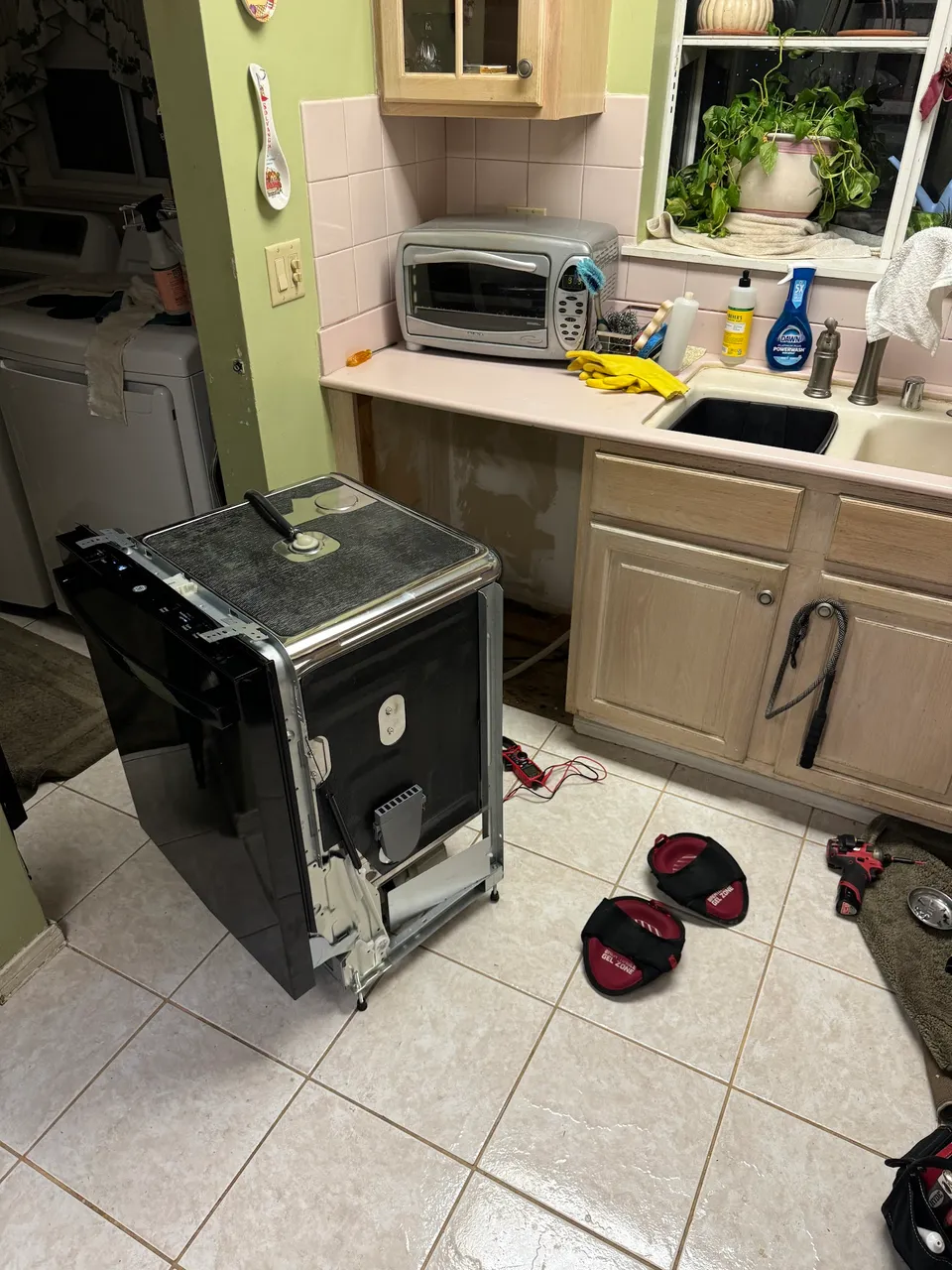 Black GE dishwasher rolled out to the middle of the kitchen for repair