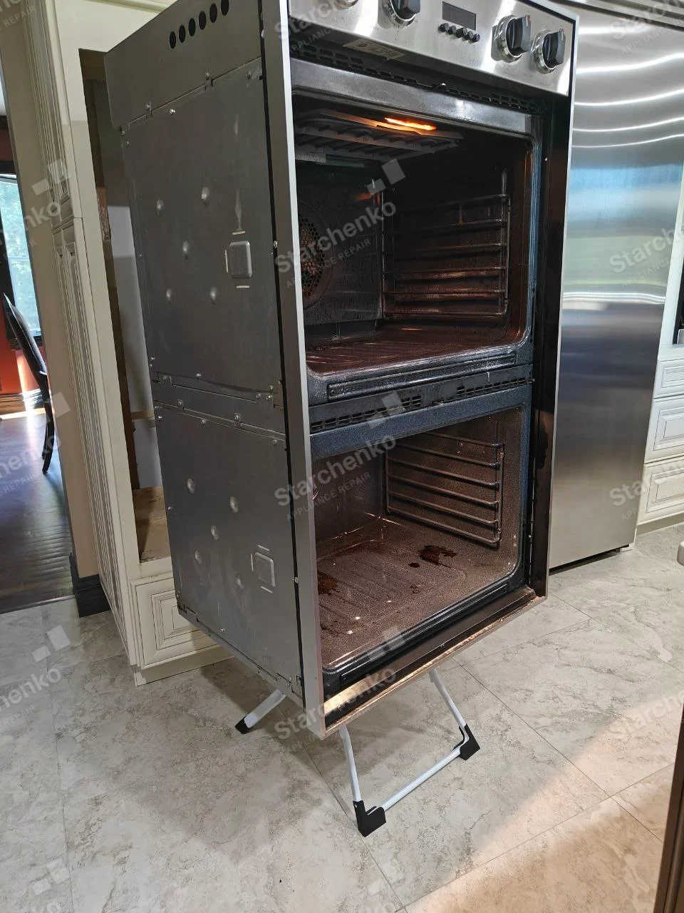 Frigidaire repair: Two oven cavities of tall double wall oven exposed after both doors removed, unit pulled out for service.