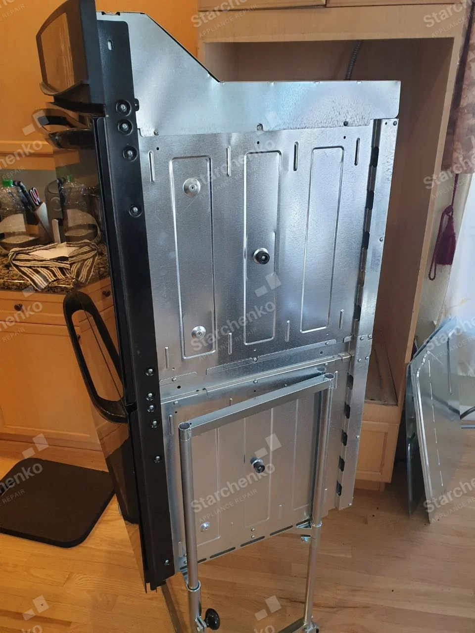 Frigidaire repair: Built-in wall oven pulled from cabinet on rolling service frame, viewed from metal side.