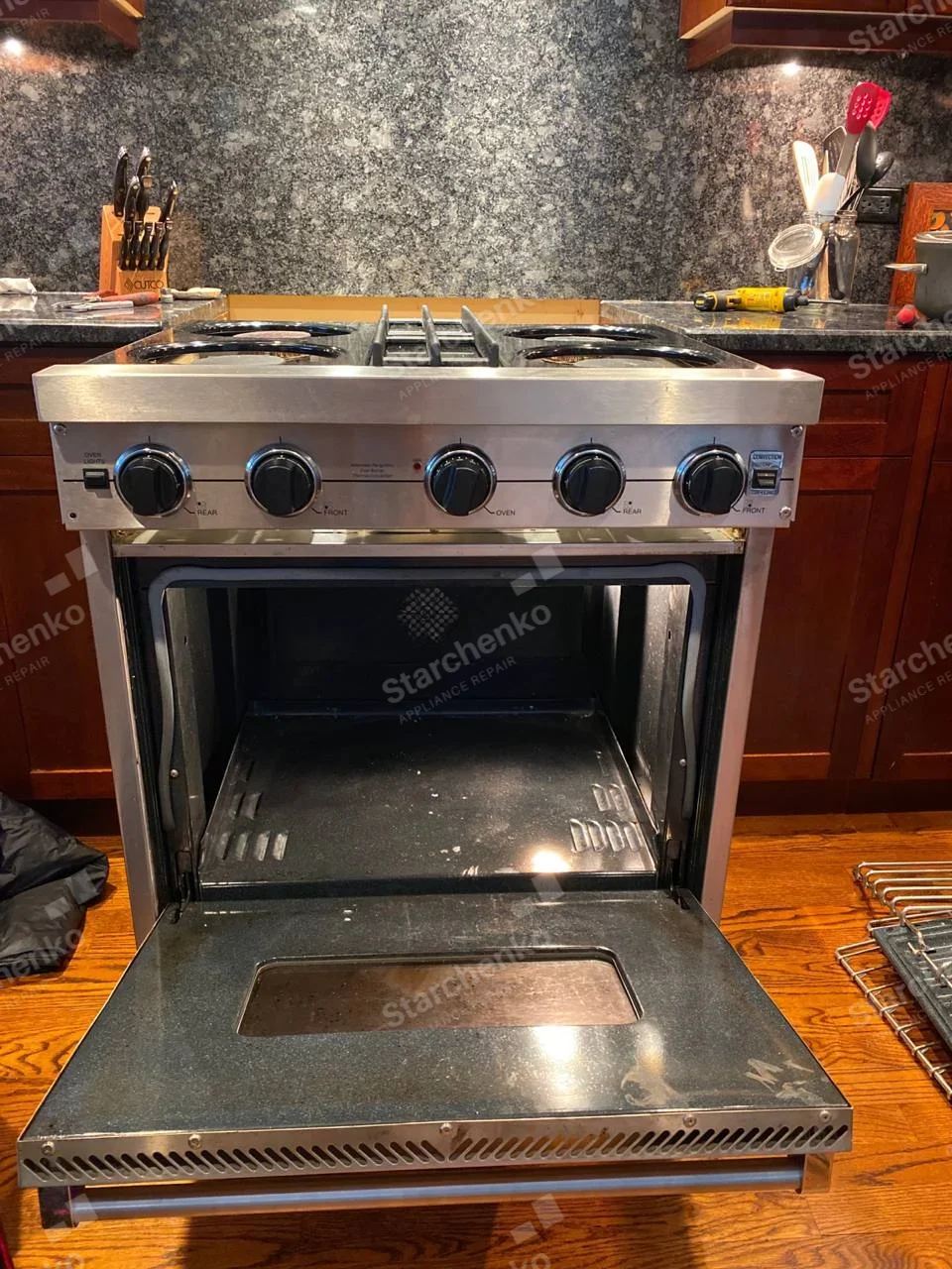 Kenmore repair: Gas range with cooktop burner assemblies removed and open oven with racks taken out.
