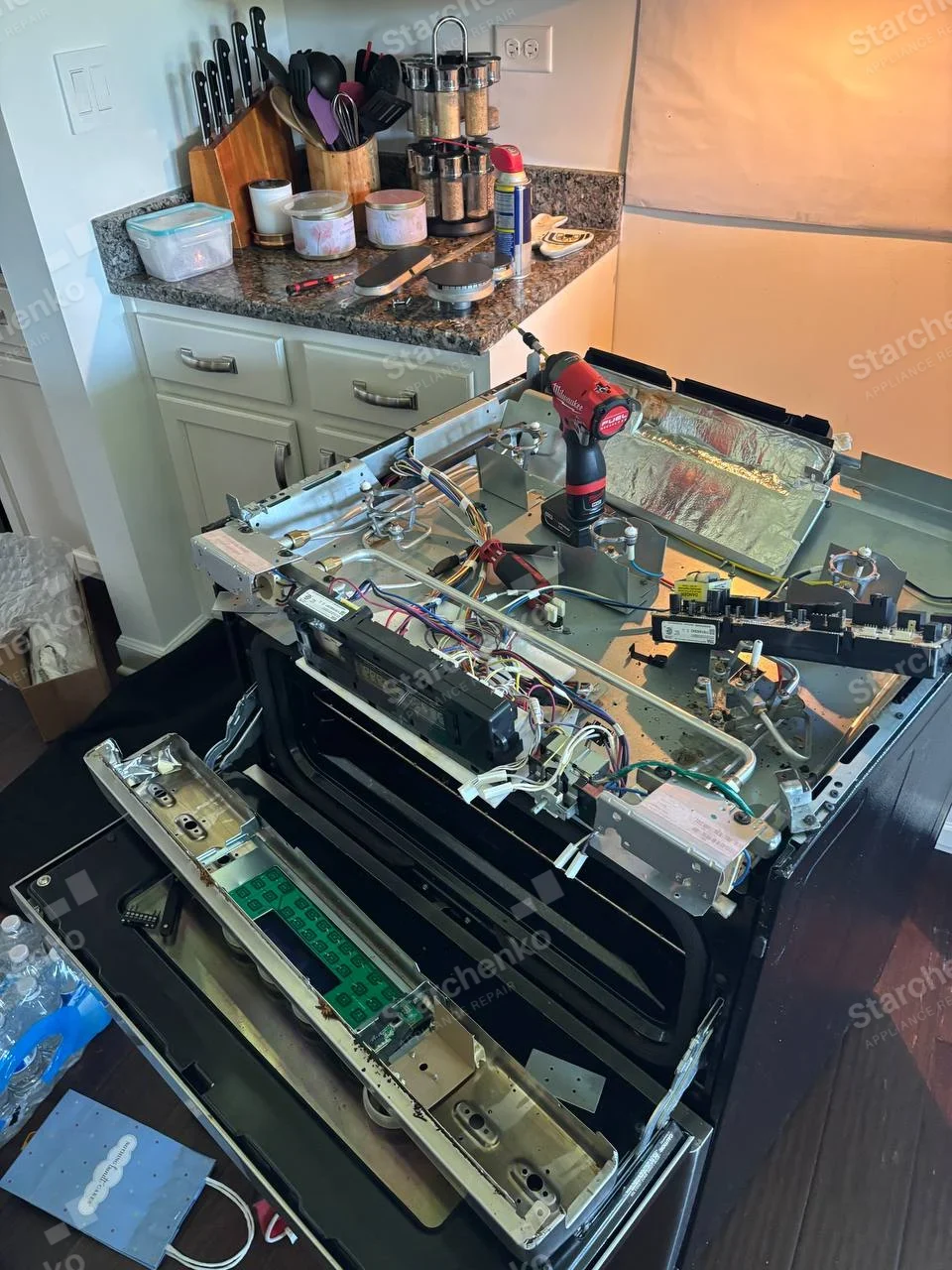 Kenmore repair: Gas range top removed showing burners, gas manifold, ignition wiring and detached front control panel.