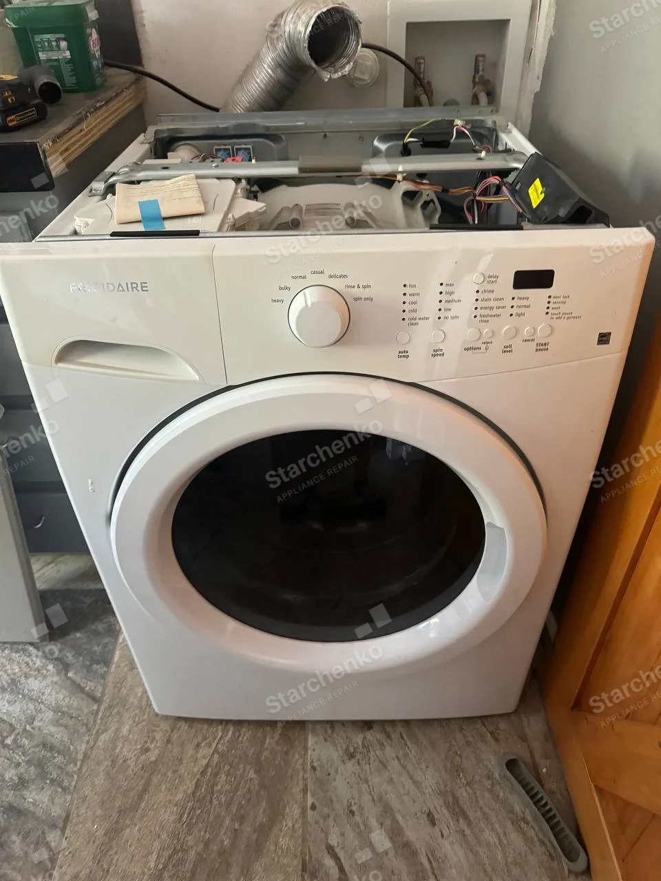 Frigidaire repair: Front-load washer with wash-cycle and spin-speed controls, top removed to expose internal wiring.
