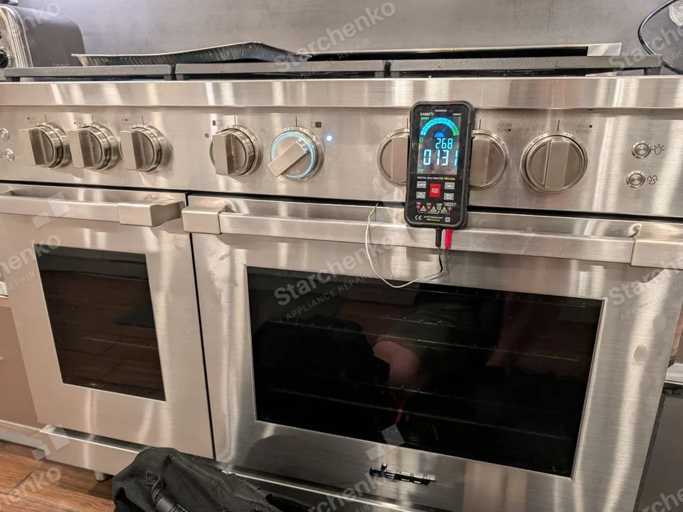 GE Monogram repair: Wide stainless cooking range with two oven doors, multiple front knobs, digital tester on handle during heat measurement.