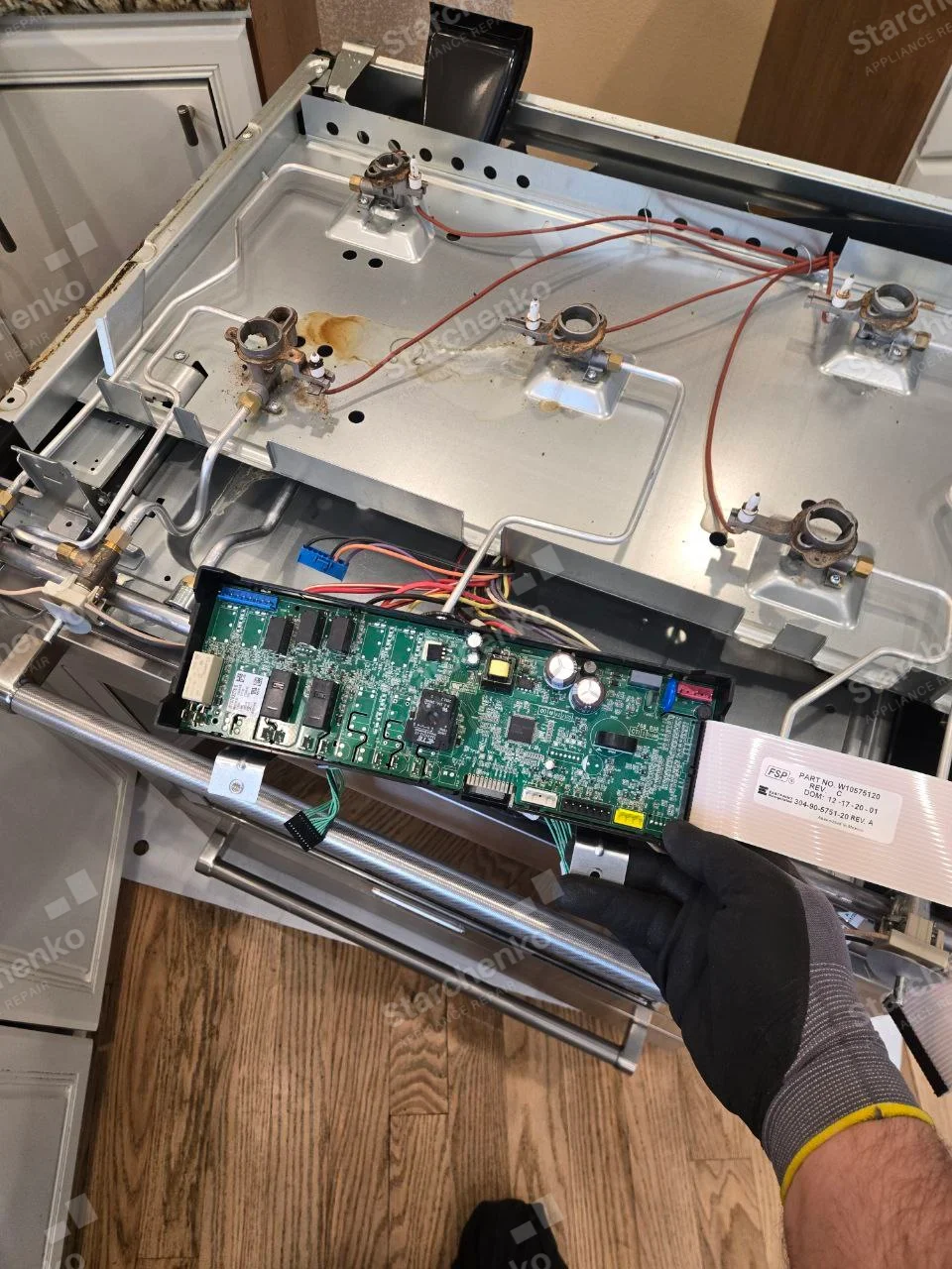 Open Frigidaire gas range cooktop with four burner bases, gas lines and control board exposed.