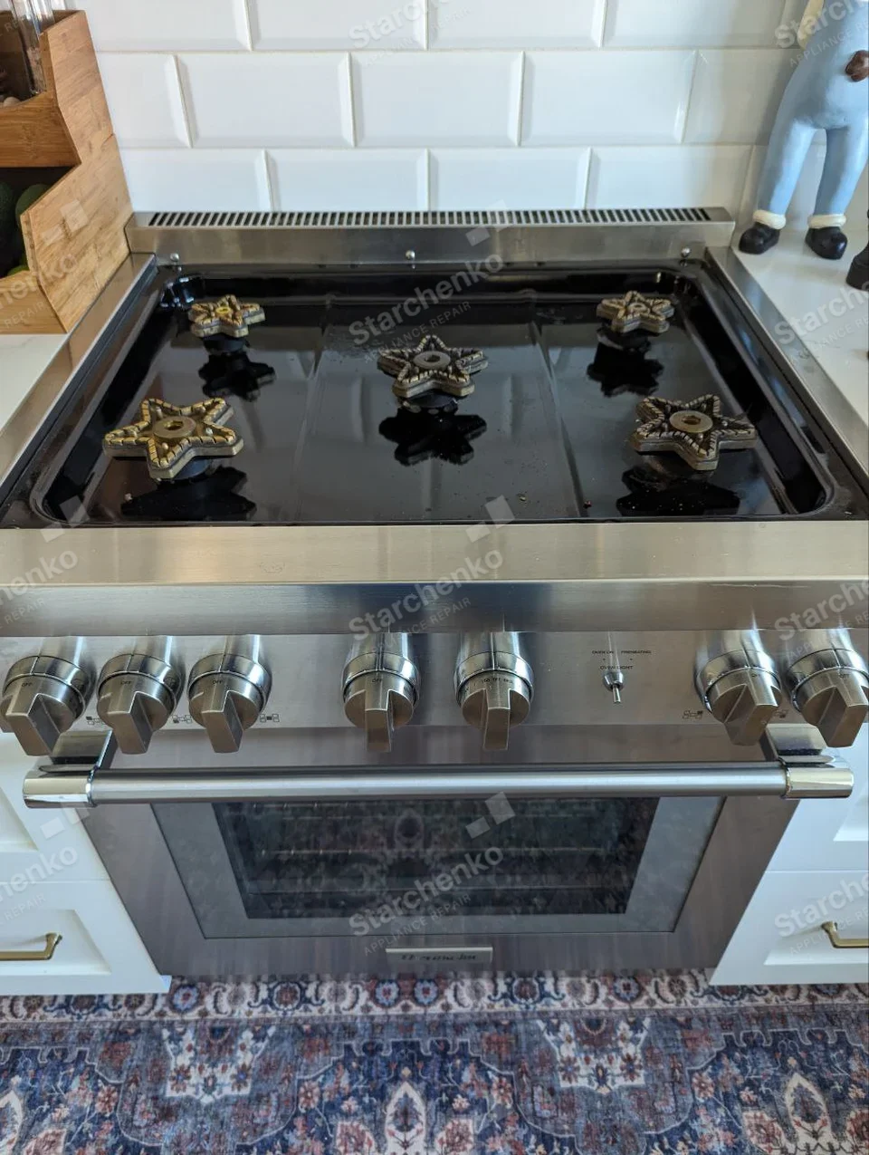 Thermador badge centered low on oven door, five star-shaped gas burners and large front controls.