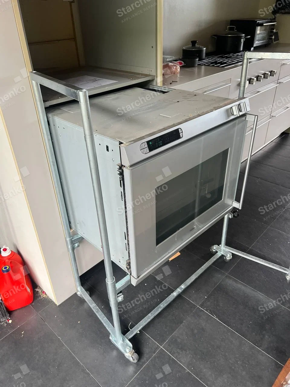 Electrolux repair: Single stainless wall oven pulled from cabinet onto wheeled service frame.
