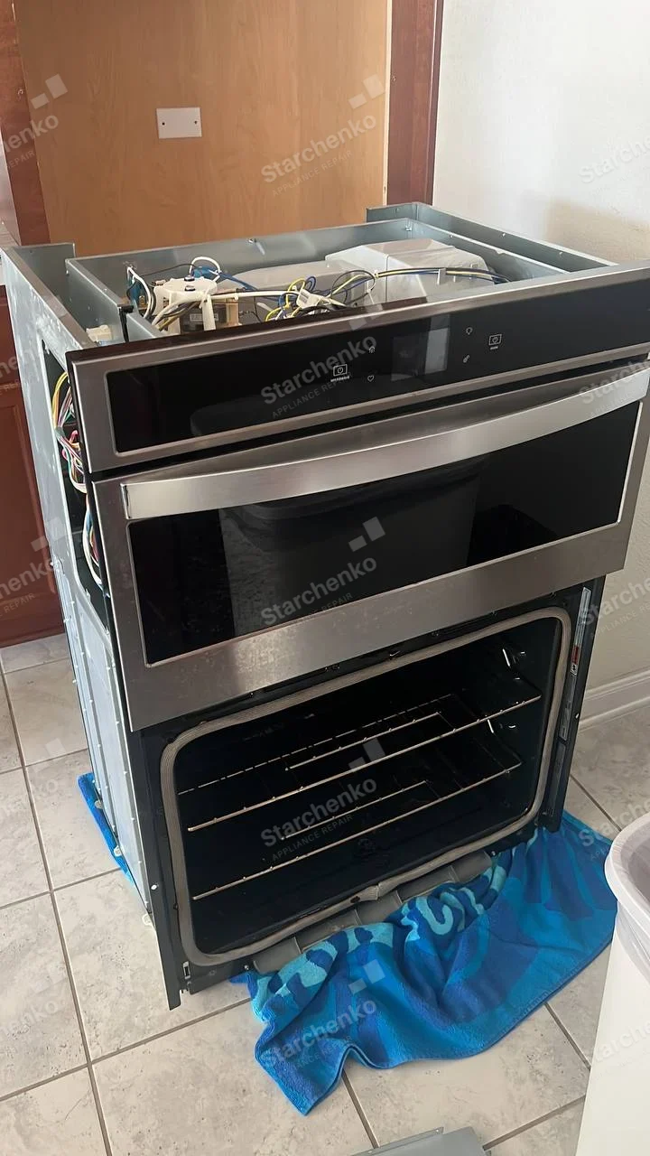 Electrolux repair: Combined built-in microwave and lower oven assembly pulled from cabinetry, top removed and oven door open.