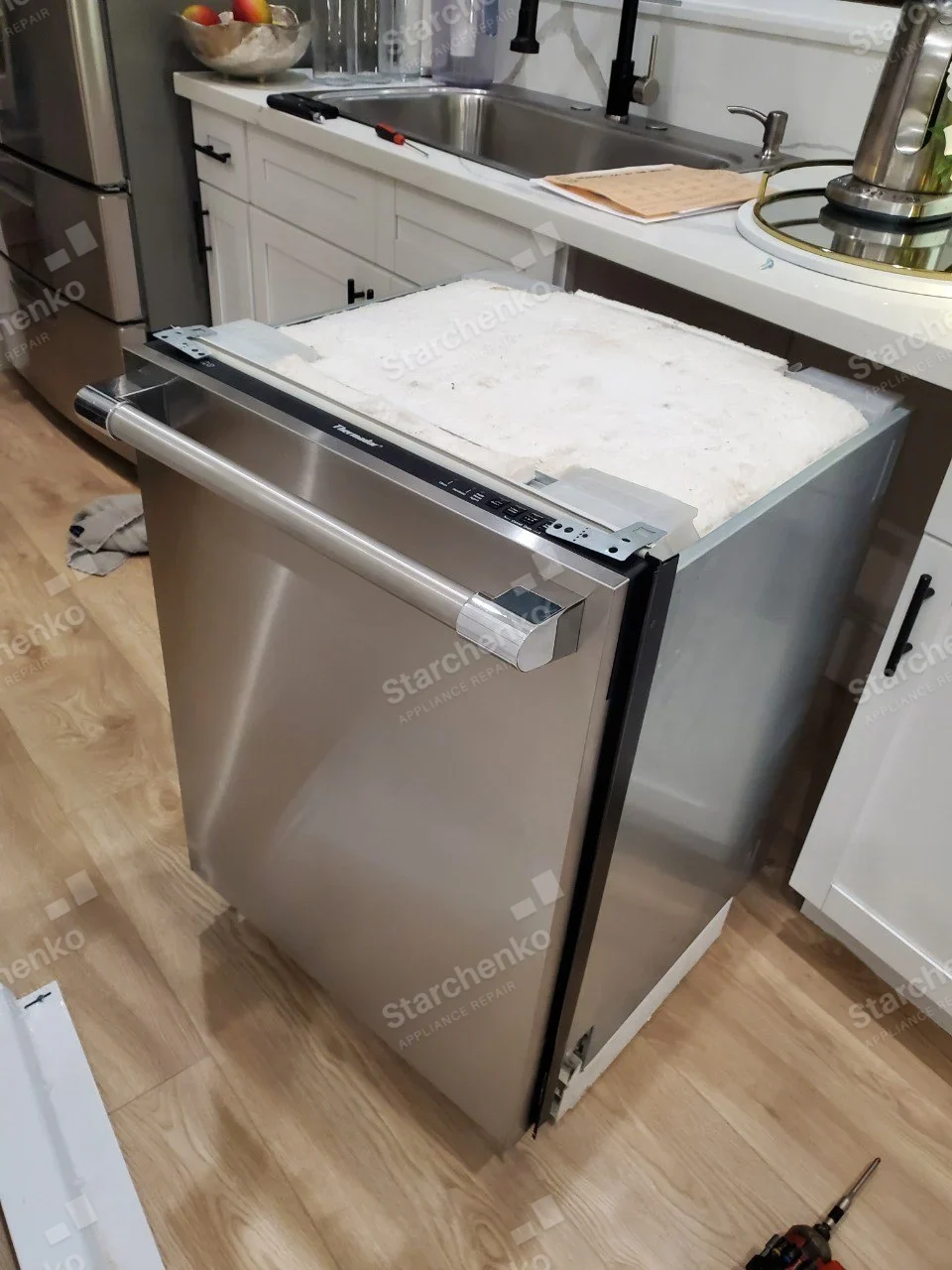 Thermador name printed across black dishwasher top-edge controls, unit pulled from cabinet with insulation across top.