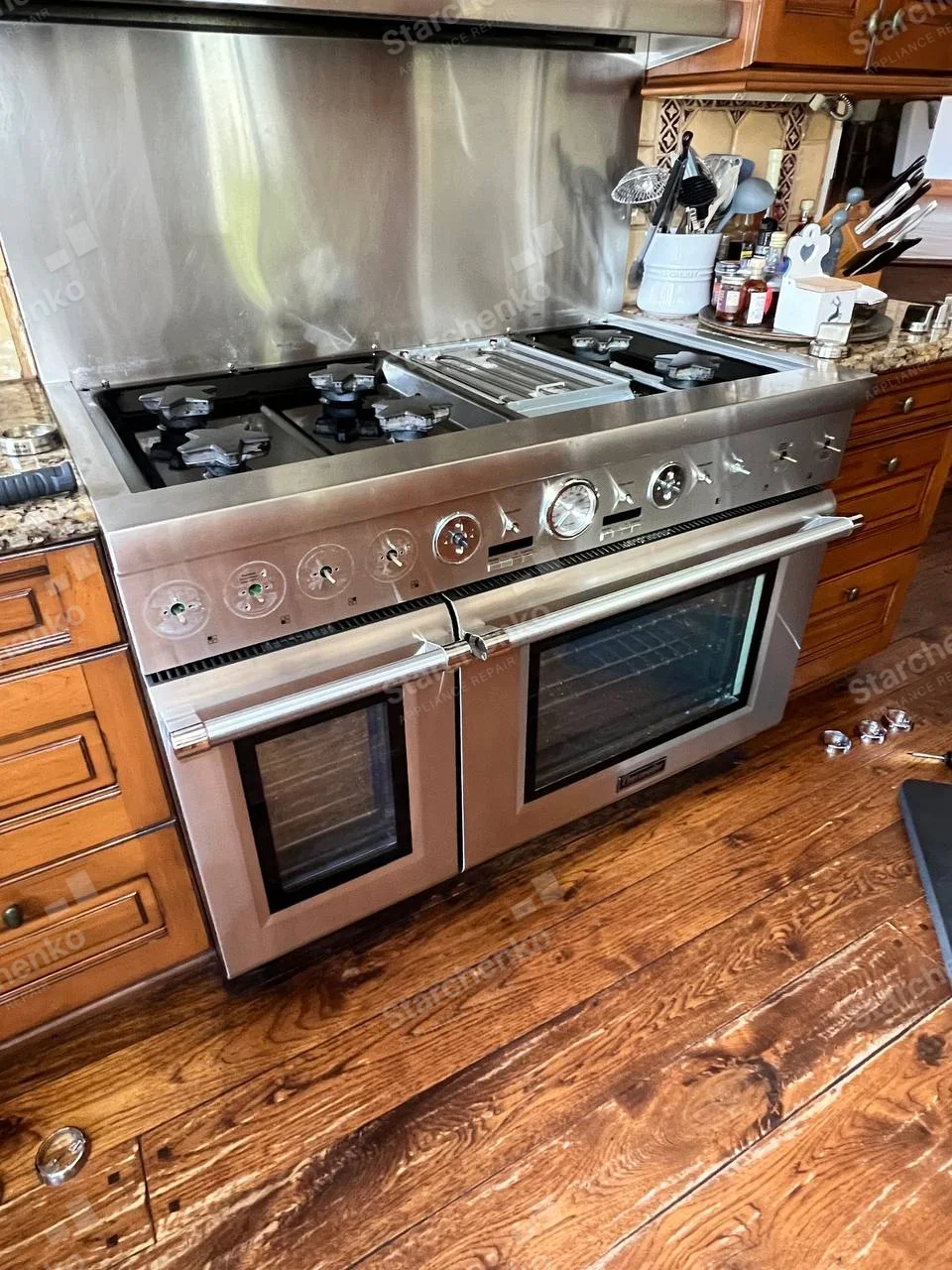 Bertazzoni repair: Wide stainless gas range with two oven doors and several control knobs removed.