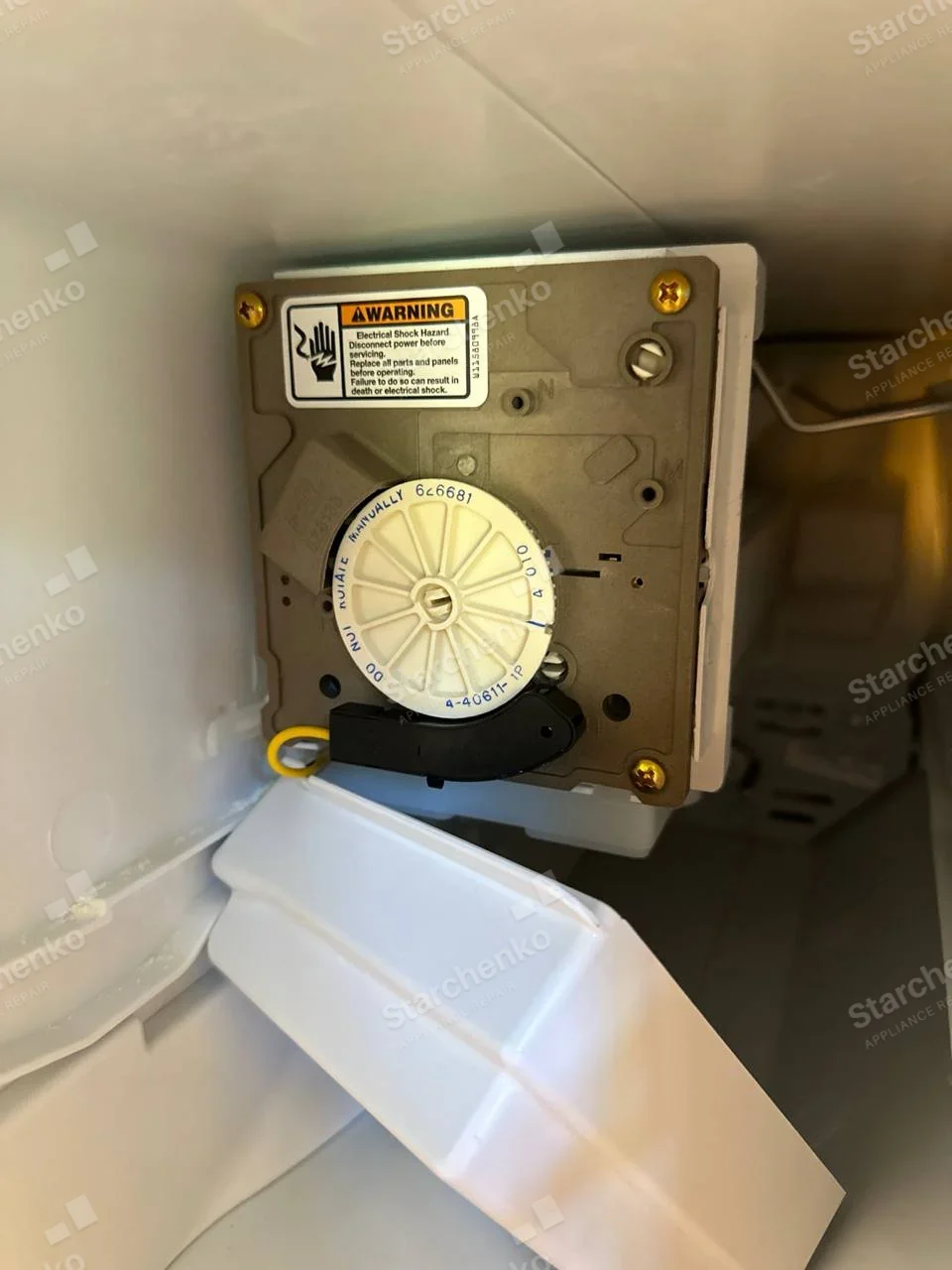KitchenAid repair: Close view of an internal freezer ice-maker control module and plastic ice chute.