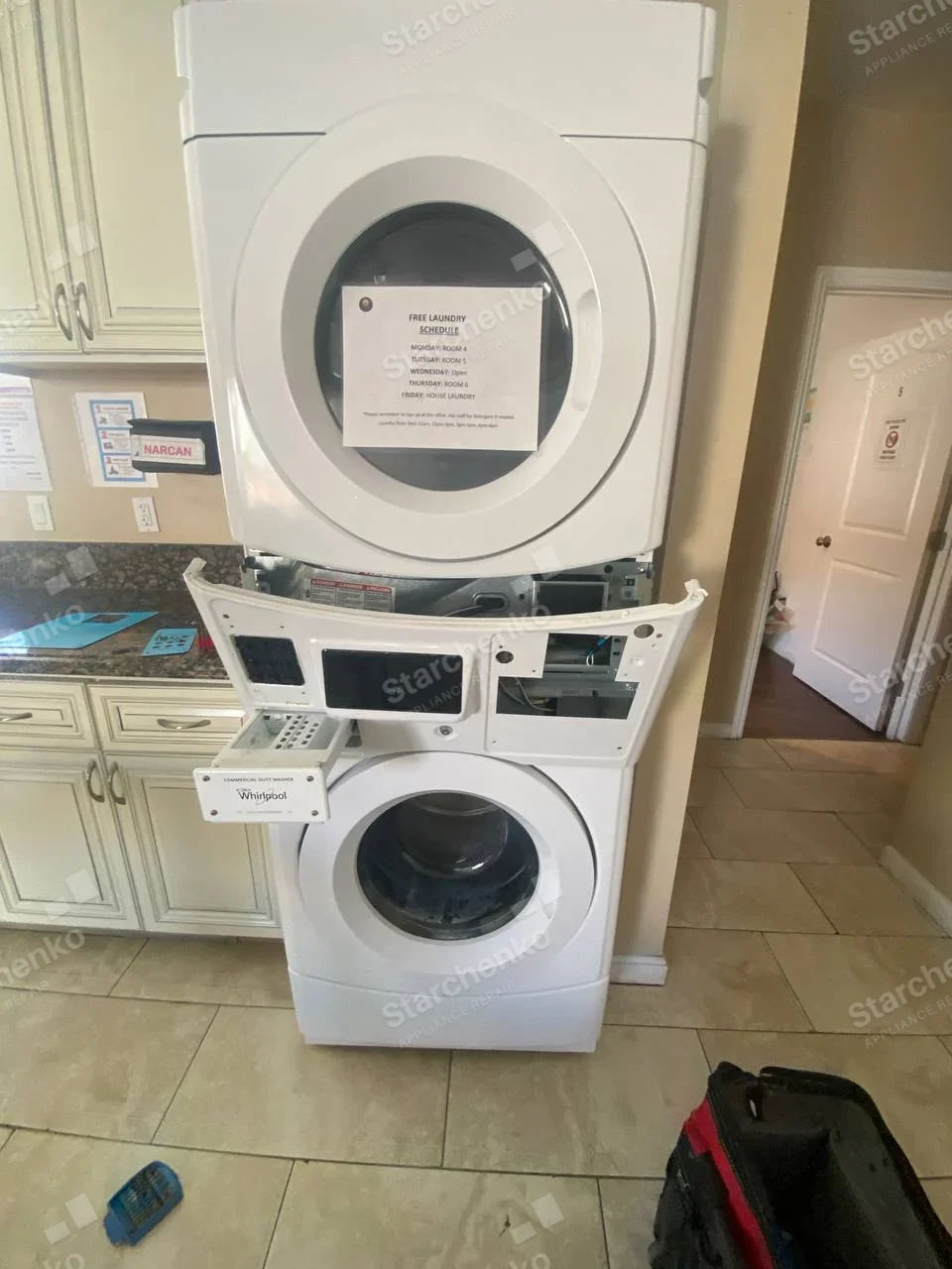 Whirlpool Commercial repair: Stacked laundry pair with lower front-load washer control panel opened beneath upper dryer.