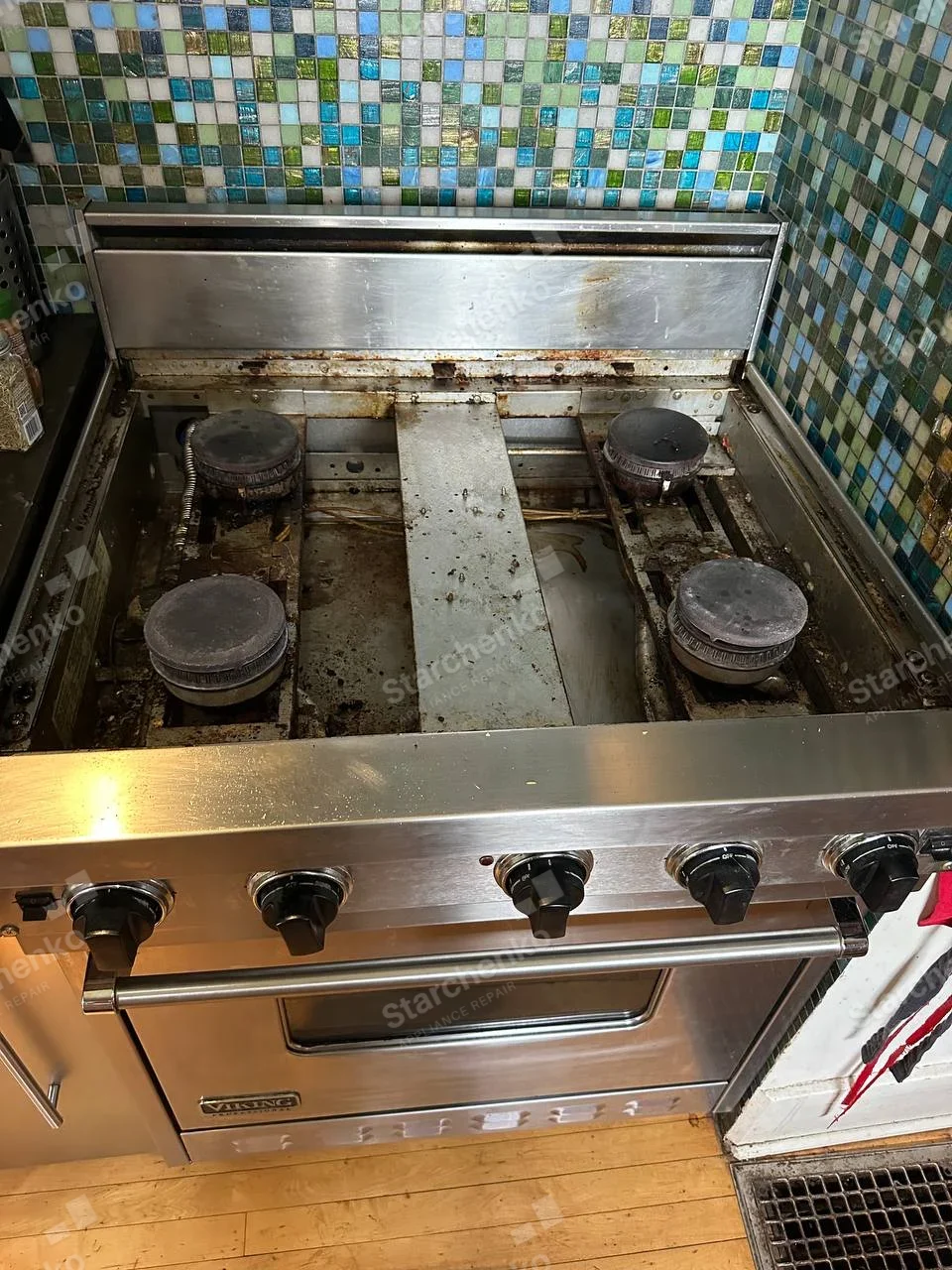 Viking badge on oven door, four exposed gas burners with grates removed above large oven.