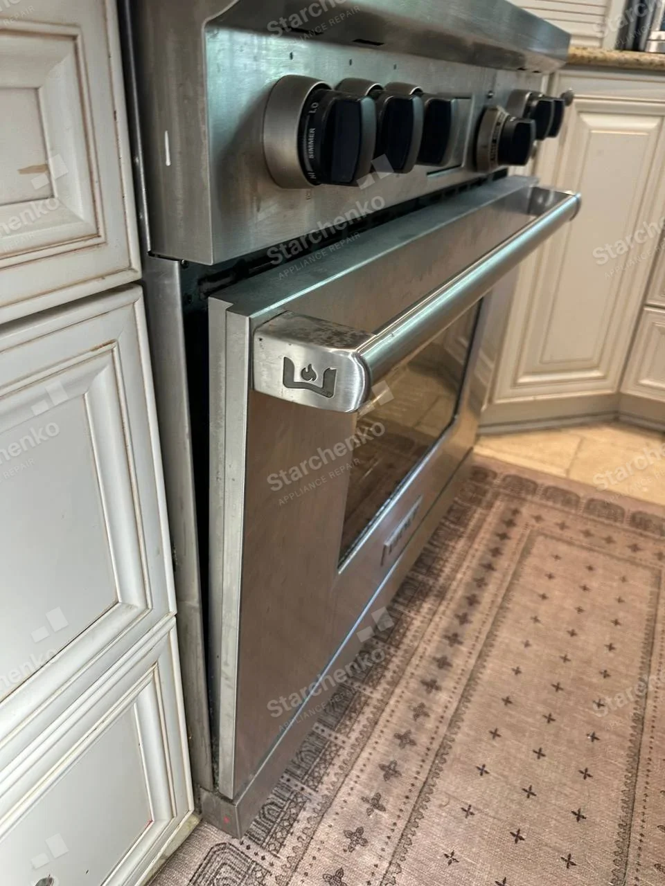 Wolf wolf-head emblem stamped on the left end of the main range oven handle.