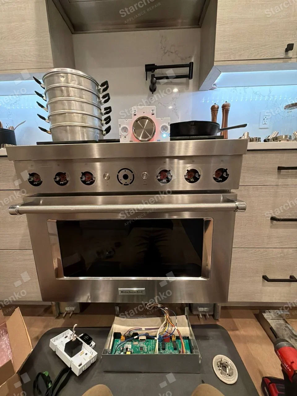 KitchenAid badge on lower center oven front of main cooking range, removed control knobs and exposed circuit board.