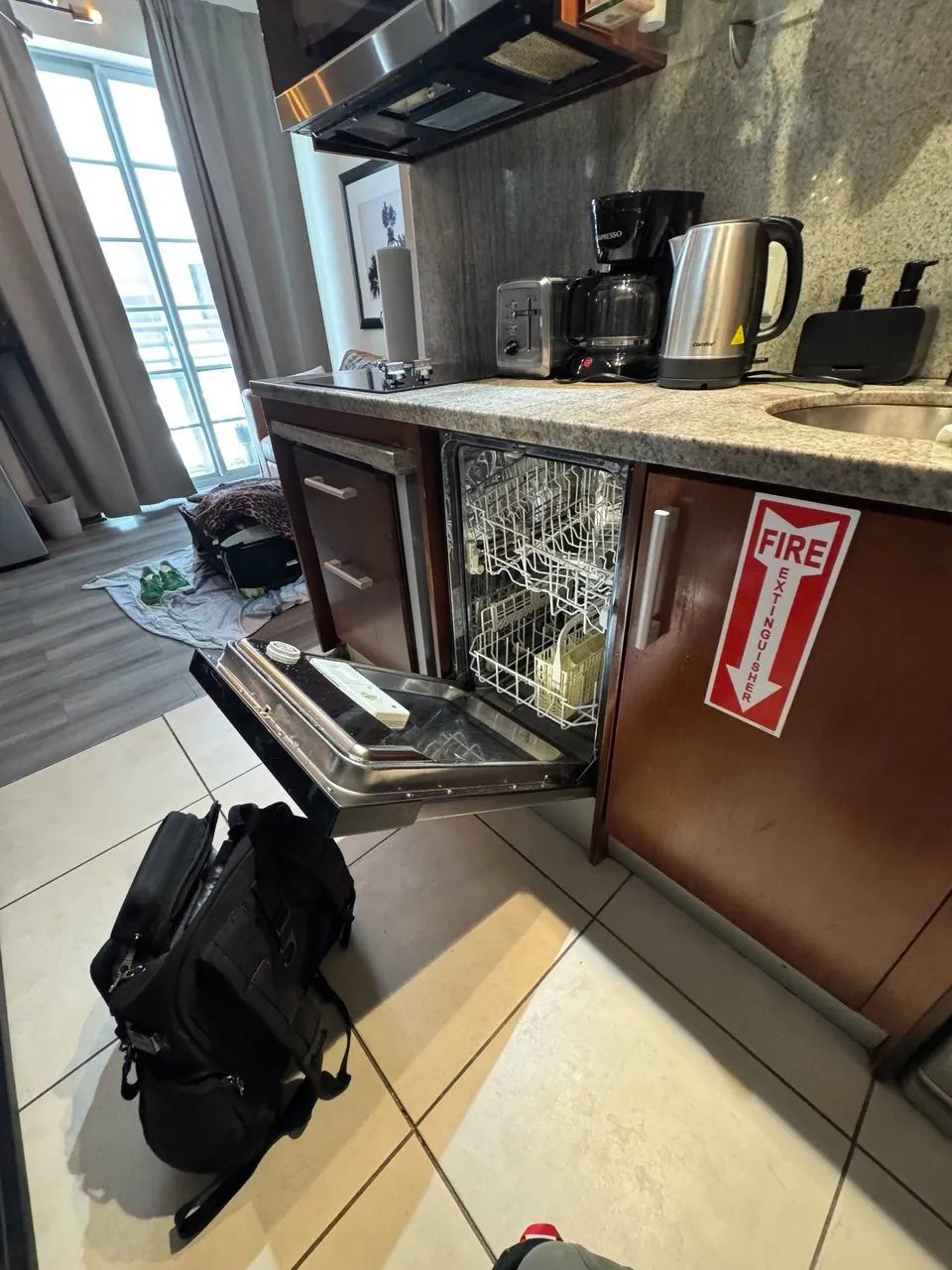 Undercounter dishwasher open under a bar counter with the racks pulled out