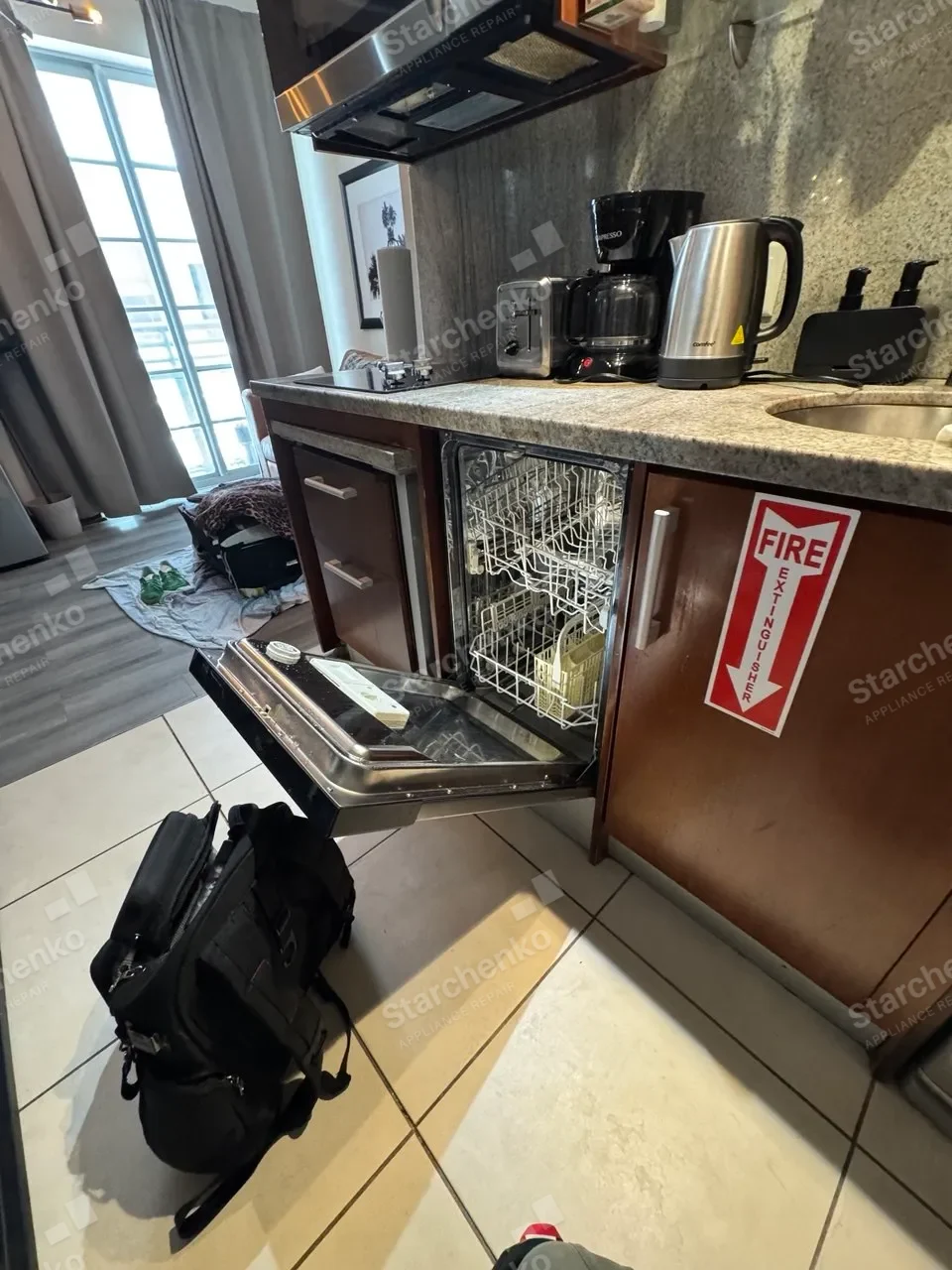 Undercounter Miele dishwasher open under a bar counter with the racks pulled out