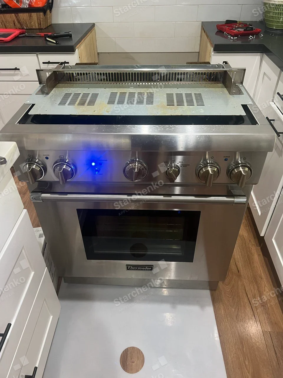 Thermador professional gas range pulled out with cooktop lifted and internal vent exposed.