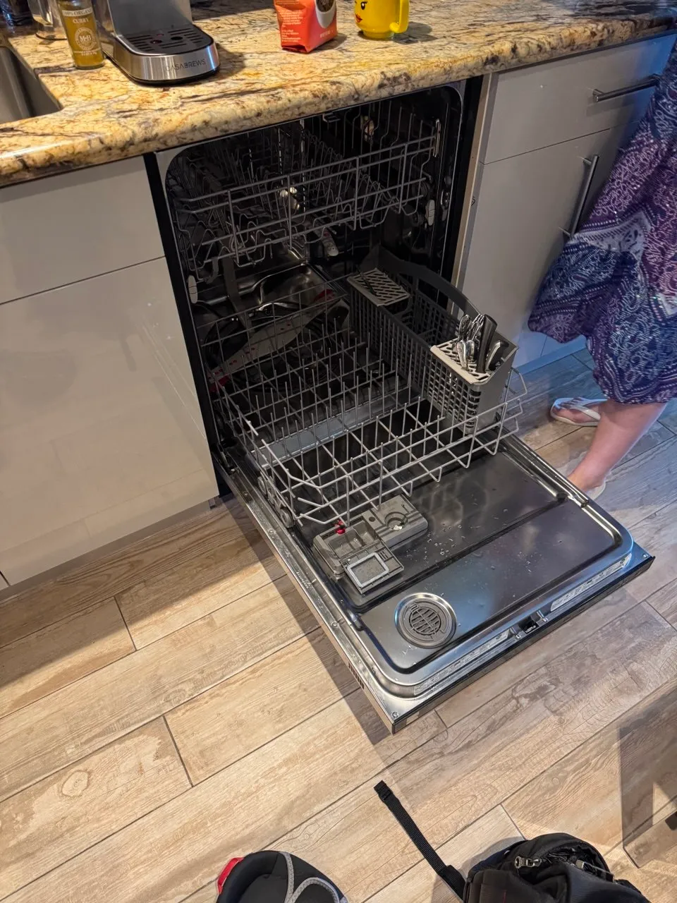 Dishwasher with the door down and the lower rack out, filter area visible