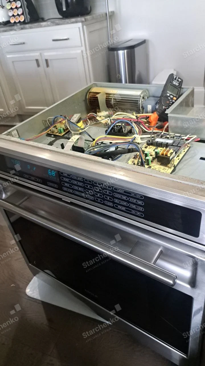 Amana repair: Electric range oven with top cooking surface removed, exposing control boards, wiring and cross-flow cooling fan.