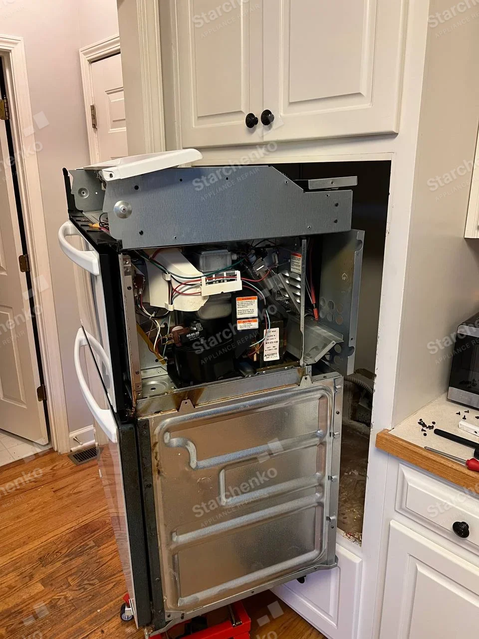 Electrolux repair: Two stacked white-handled oven doors, pulled-out unit exposes upper internal electronics and rear panel.