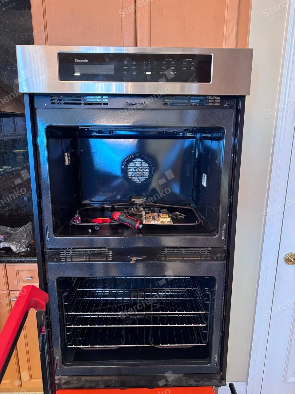 Thermador name on upper-left fascia of main built-in double oven, upper compartment and electronics exposed.