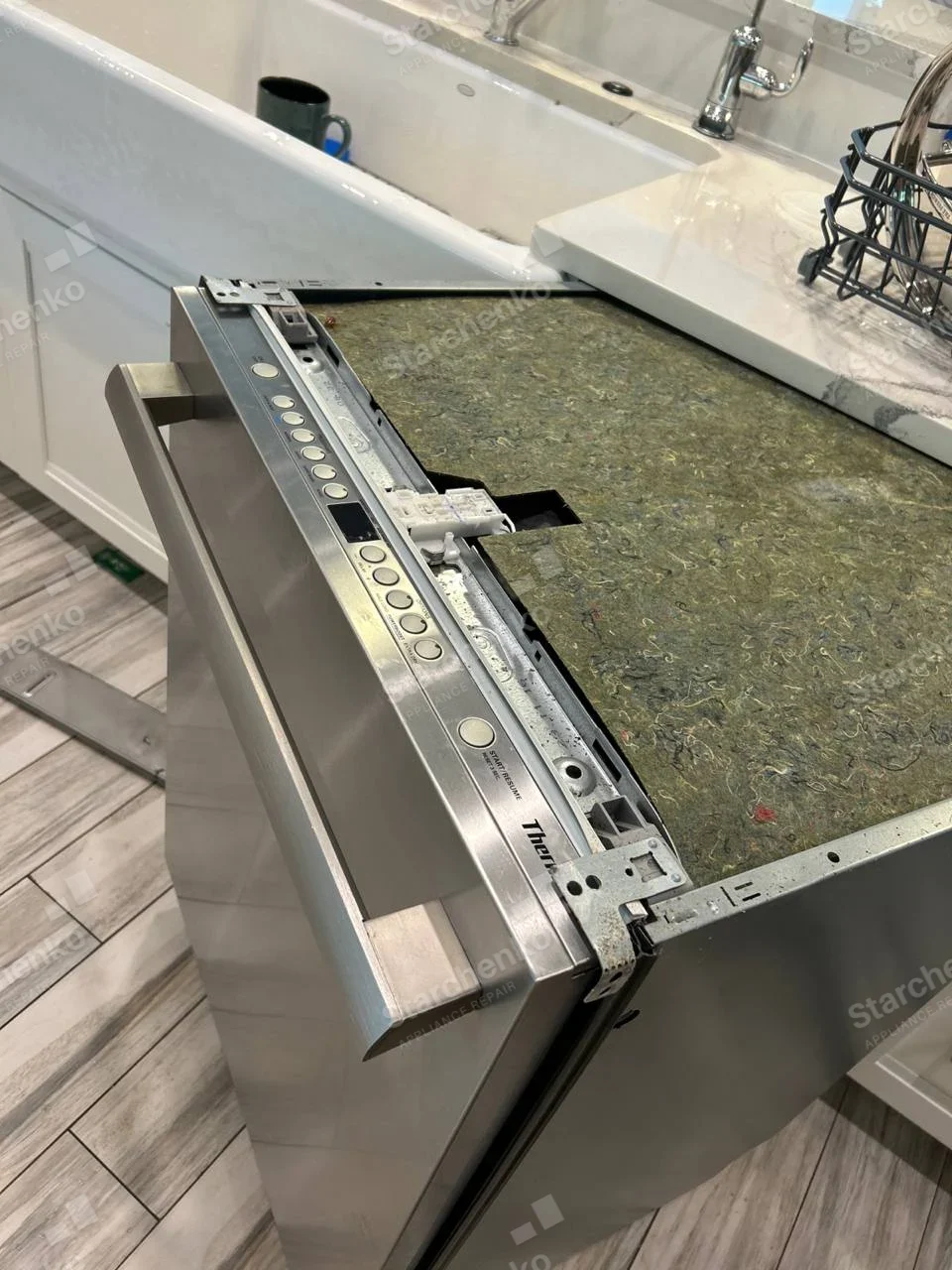 Dishwasher pulled out, top insulation exposed and control console open, Thermador wordmark on right end of control strip.