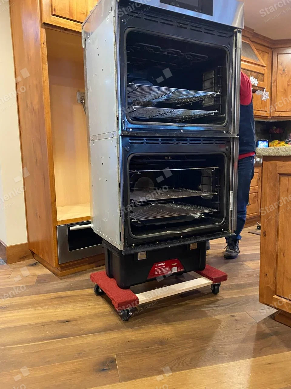 Electrolux repair: Double wall oven on wheeled dolly with upper and lower cavities exposed and doors removed.