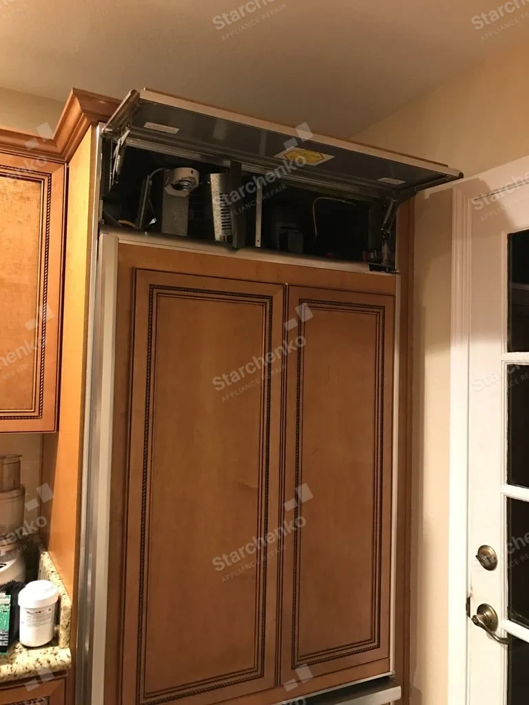 Viking repair: Panel-ready built-in refrigerator with top service grille raised and mechanical bay visible.
