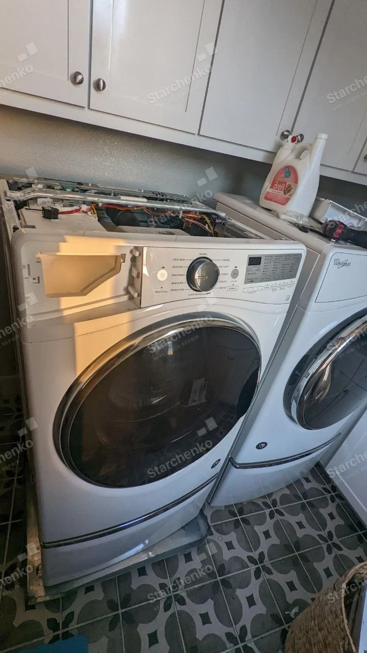 Frigidaire repair: Left front-load washer with top cover removed and detergent drawer area opened, beside another washer.